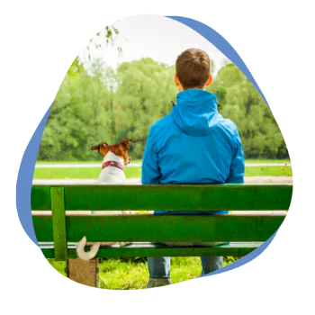 Mann mit seinem Hund auf einer grünen Bank sitzend
